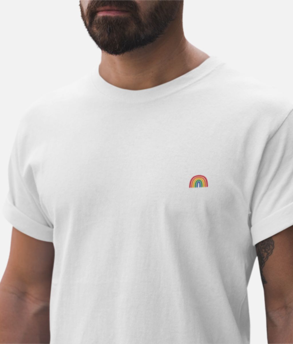 A man wears a white t-shirt with a small rainbow printed on the front, representing support for LGBTQ+ communities.