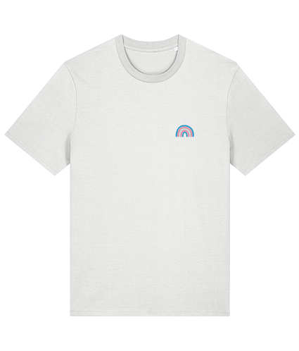 White t-shirt featuring a trans rainbow logo, smiling and standing against a neutral background.